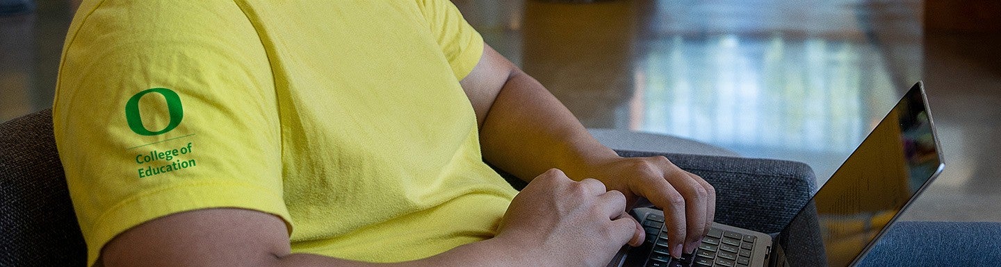 person working on laptop wearing yellow UO shirt