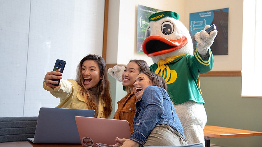 three female students taking a selfie with the oregon duck