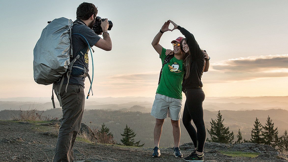 person taking photos of two people at the top of spencers butte