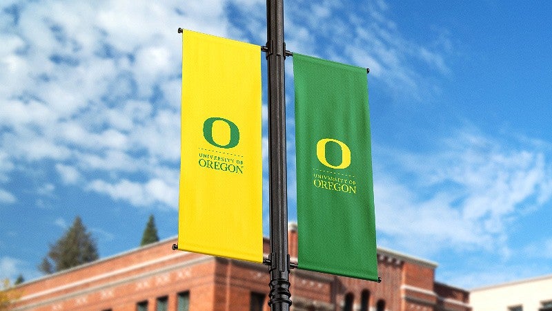 one yellow and one green banner with the UO logo, mounted on a pole