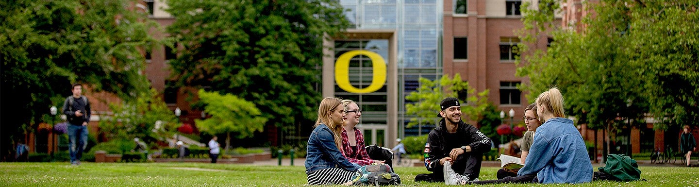 students sitting on lawn on UO campus