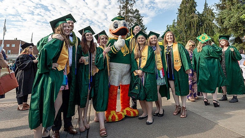 a group of UO students posing with the Duck on graduation day