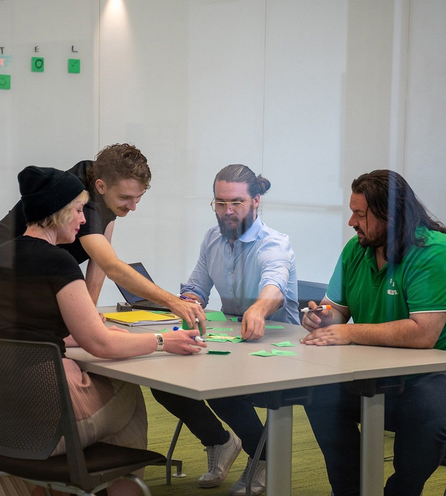 four people working at a table with markers and sticky notes
