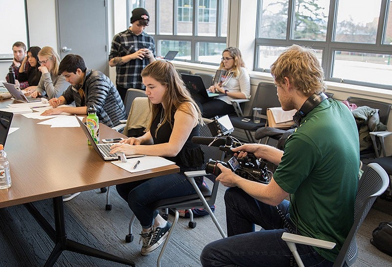 a photo of a videographer taking video of students in a classroom