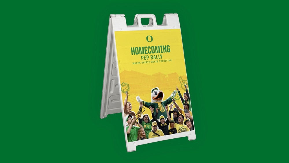 Homecoming pep rally sandwich board featuring the Duck and people cheering