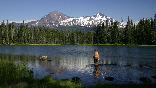 man stands in scott lake with mountain in the background
