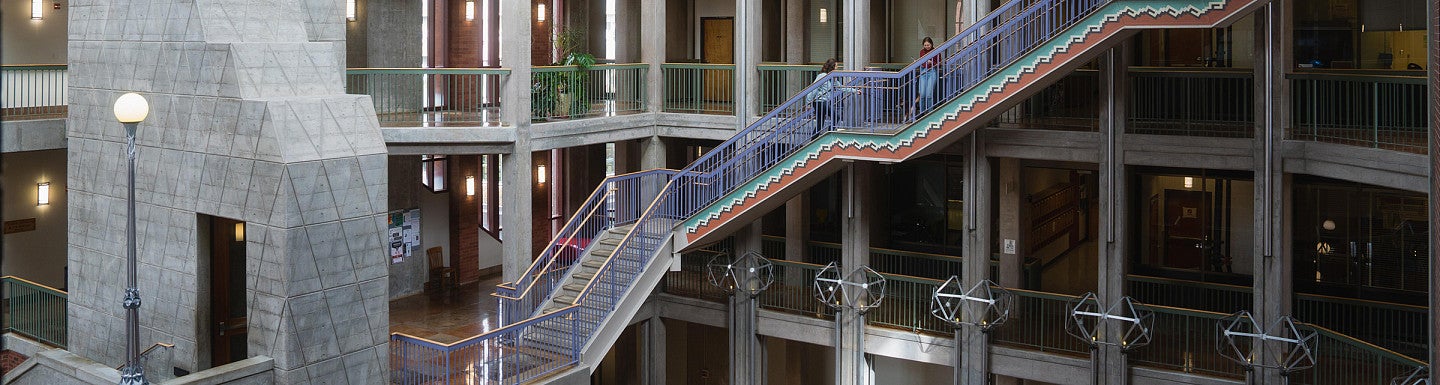 two students standing on a set of stairs in the willamette hall atrium