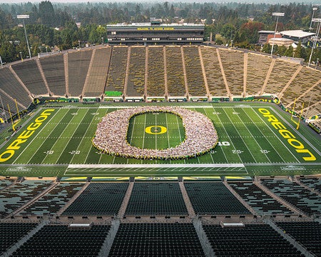 students arranged on a football field forming the oregon o