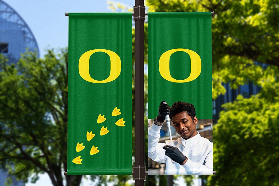 two green pole banners with a pattern of duck feet, a scientist, and the oregon o