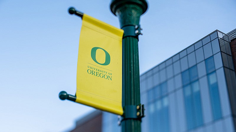 yellow pole banner with a green university of oregon primary mark
