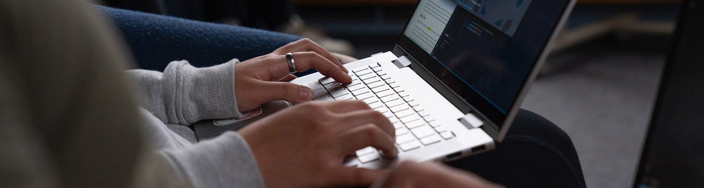 a pair of hands typing on a laptop