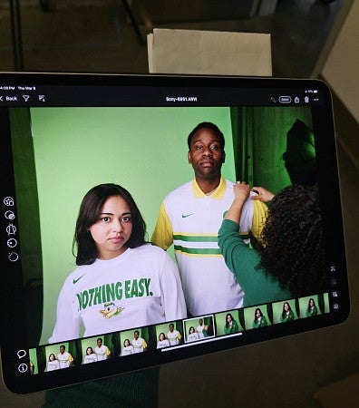 Academy students posing for a photoshoot, while one gets their shirt fixed